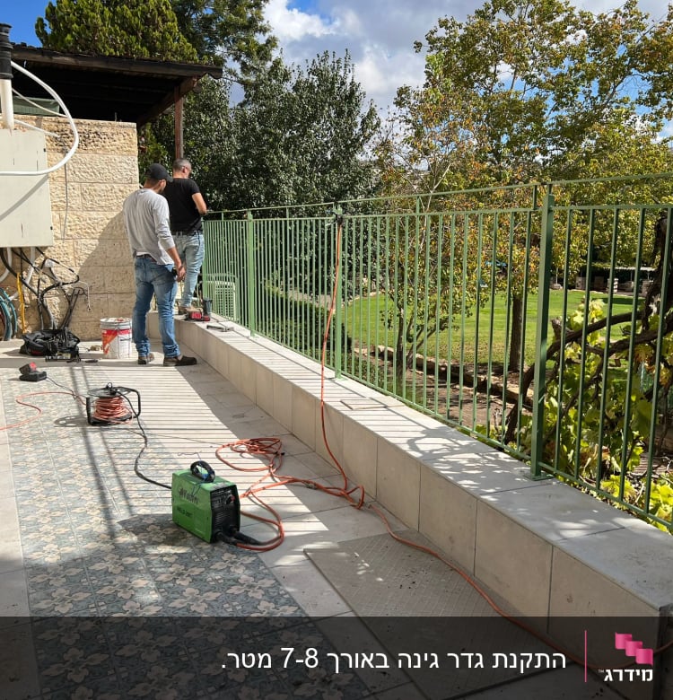 שני אנשים עובדים ליד מעקה ירוק עם כבלים וכלים